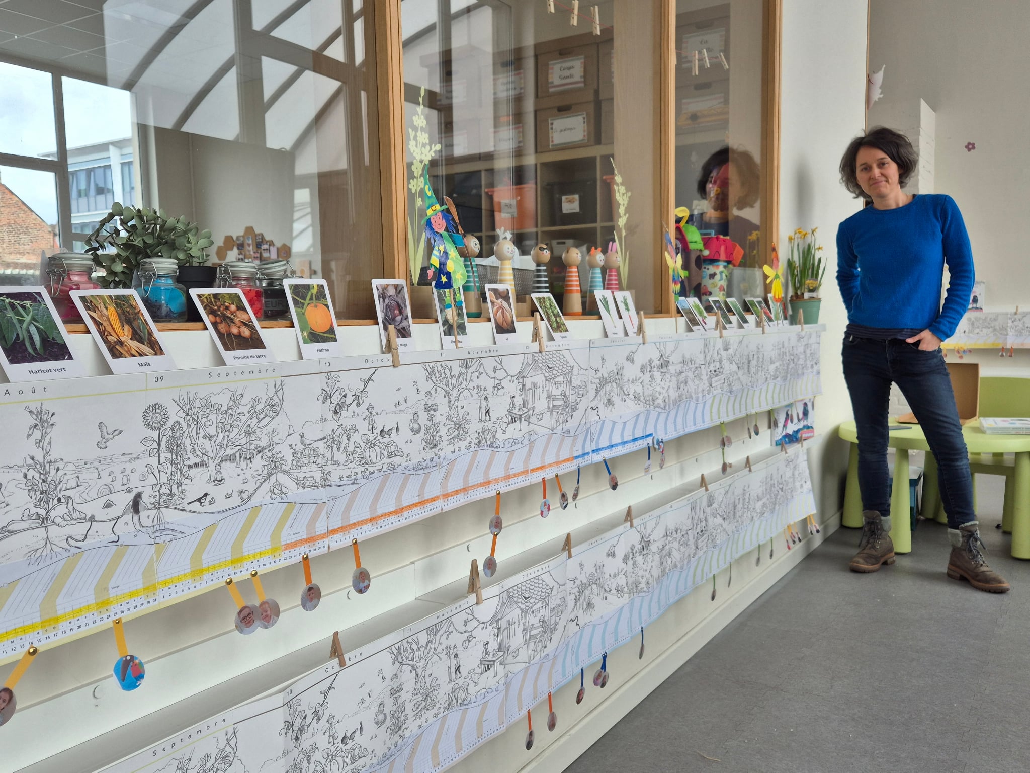 Laetitia avec les deux Calendriers Panoramiques affichés au mur chez les 1ères maternelles au CSM