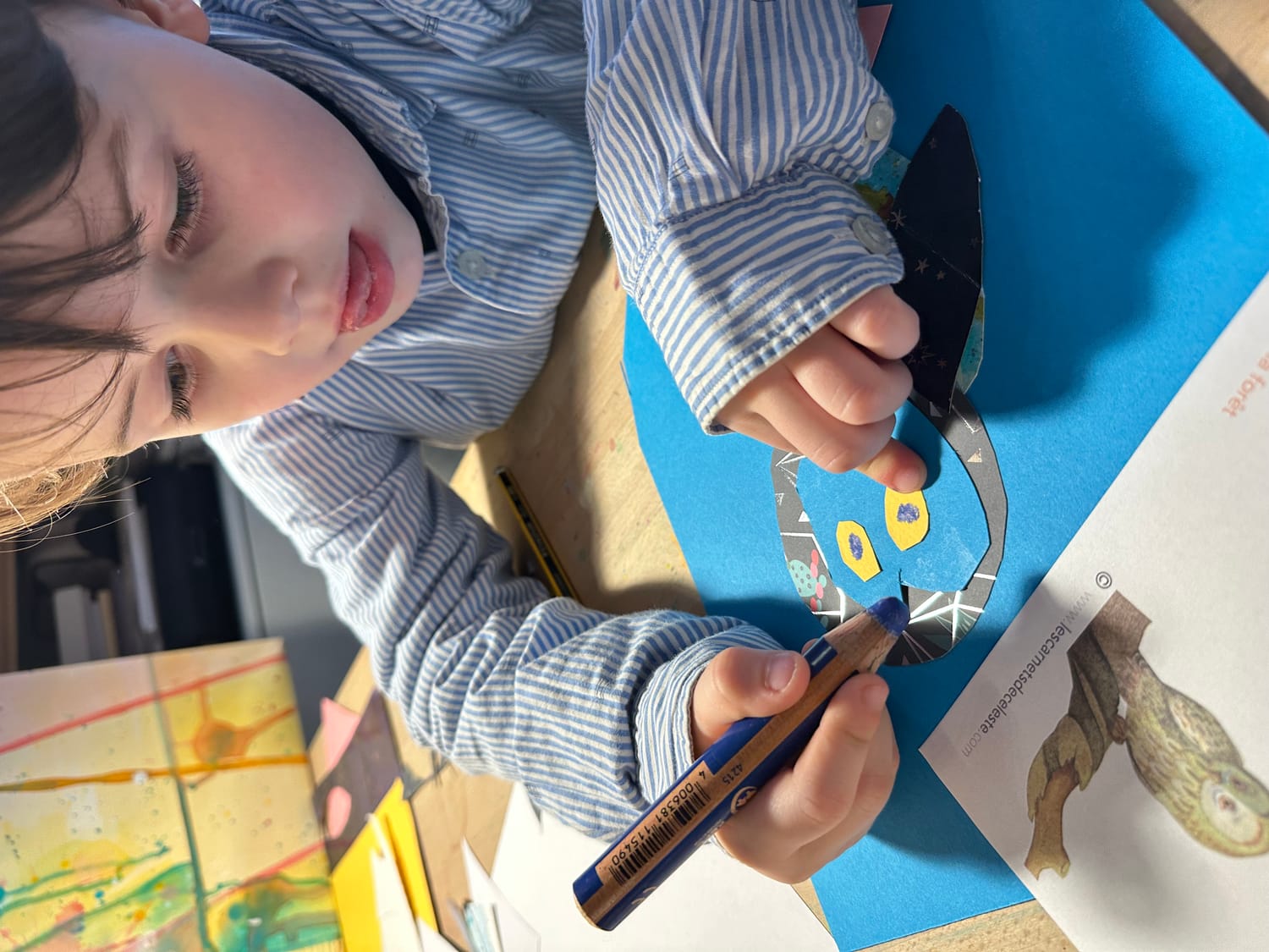 Baptiste dessine les yeux de la chouette au crayon