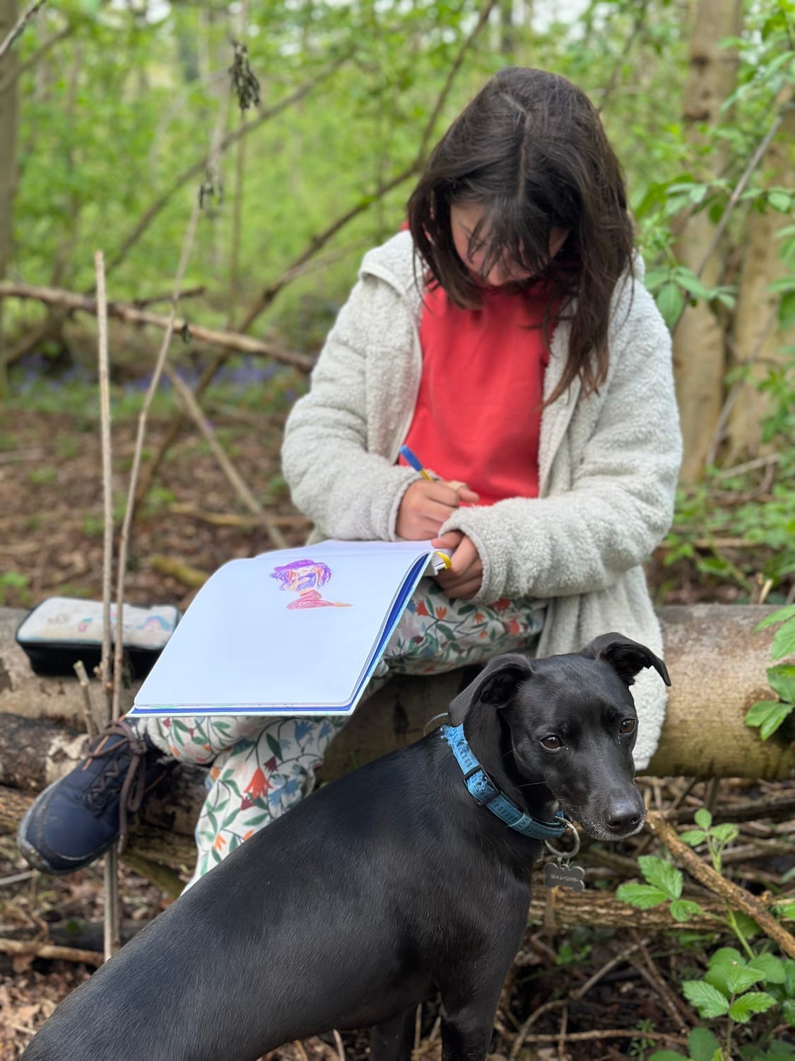 Céleste dessine dans la forêt entourée de jacinthes des bois