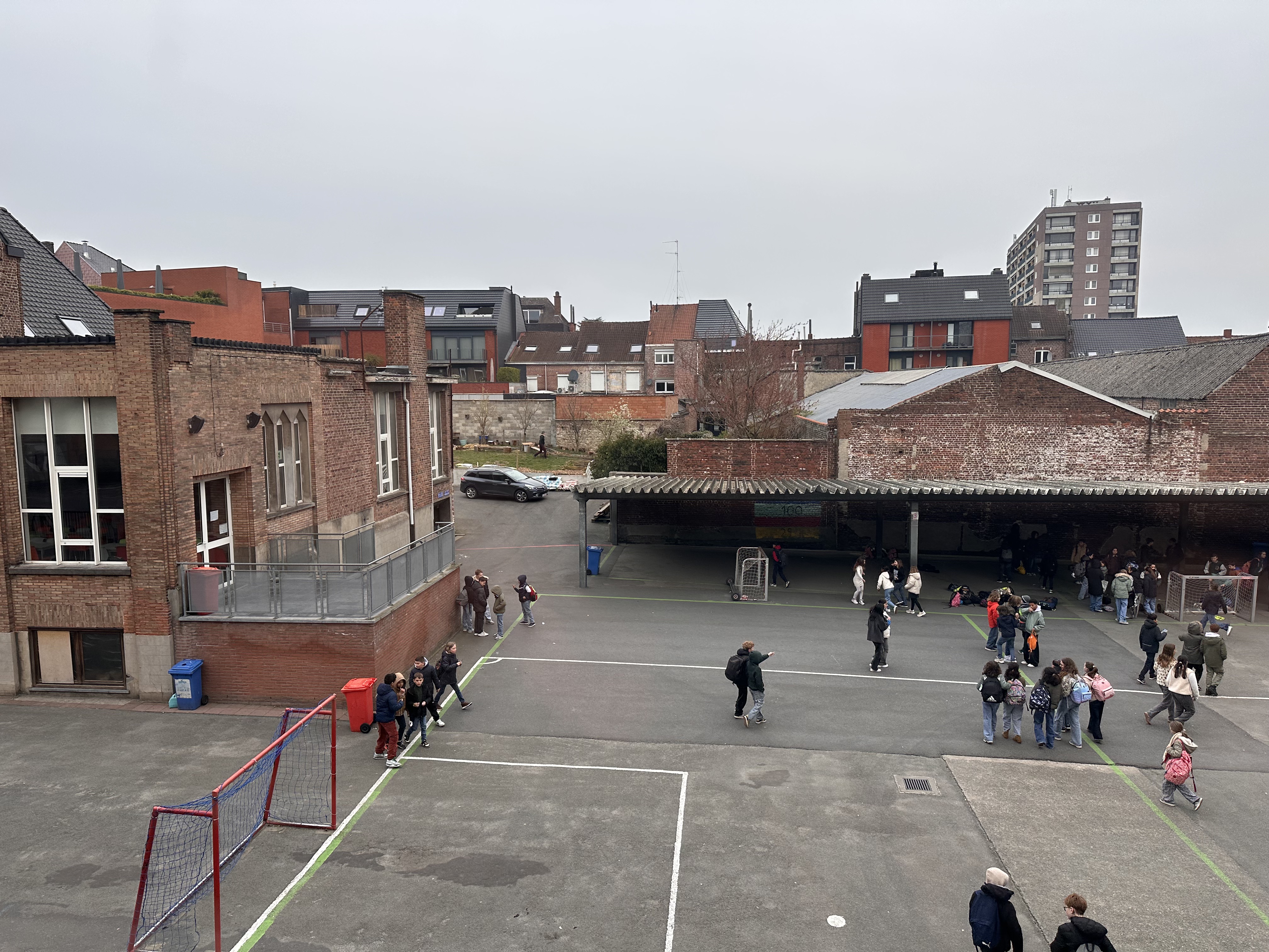 Vue plongeante de la cour de récréation du CSM depuis le premier étage, avec les maisons du quartier en arrière-plan