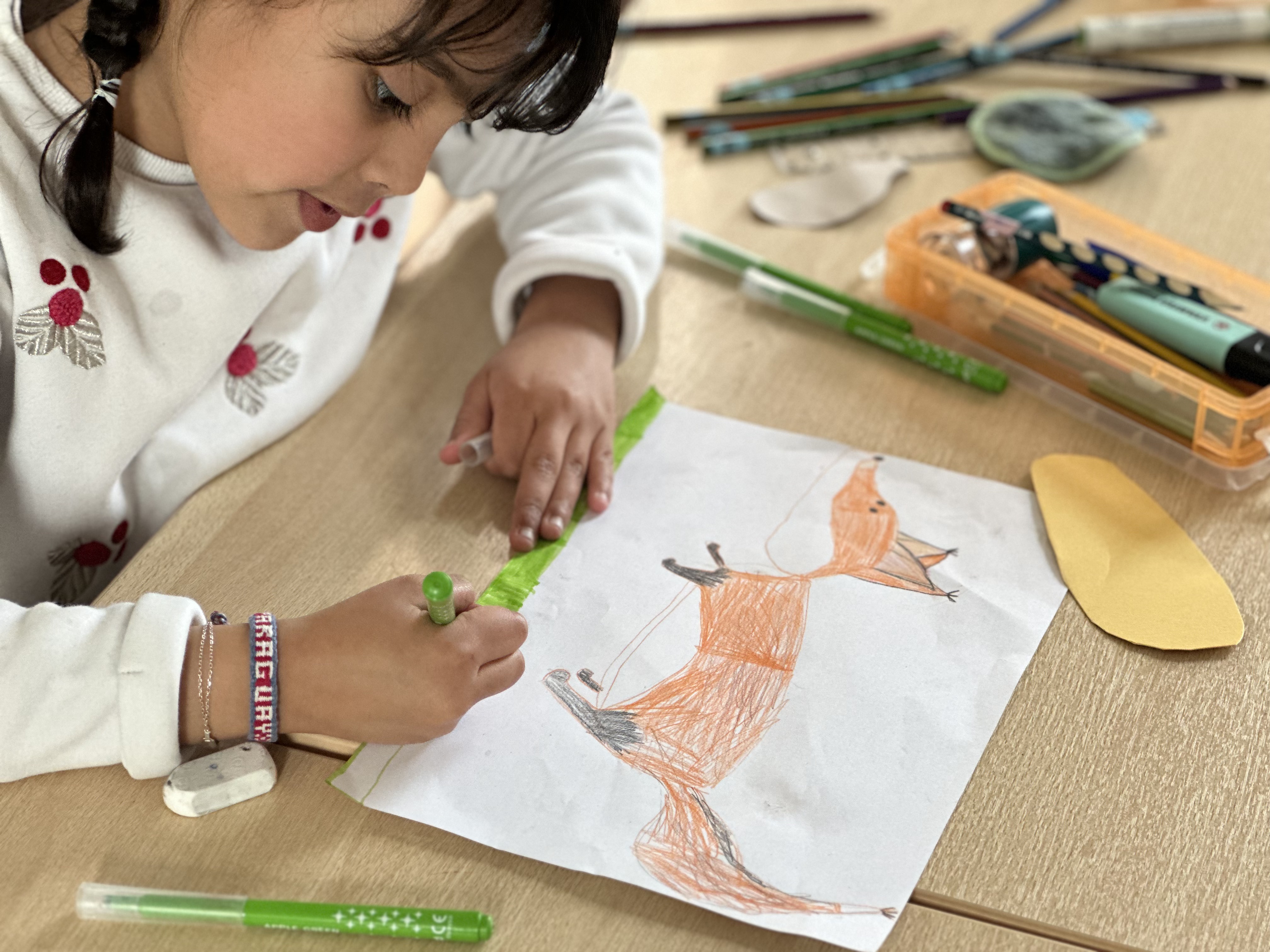 Une enfant de 6 ans du CSM termine son dessin de renard en atelier créatif