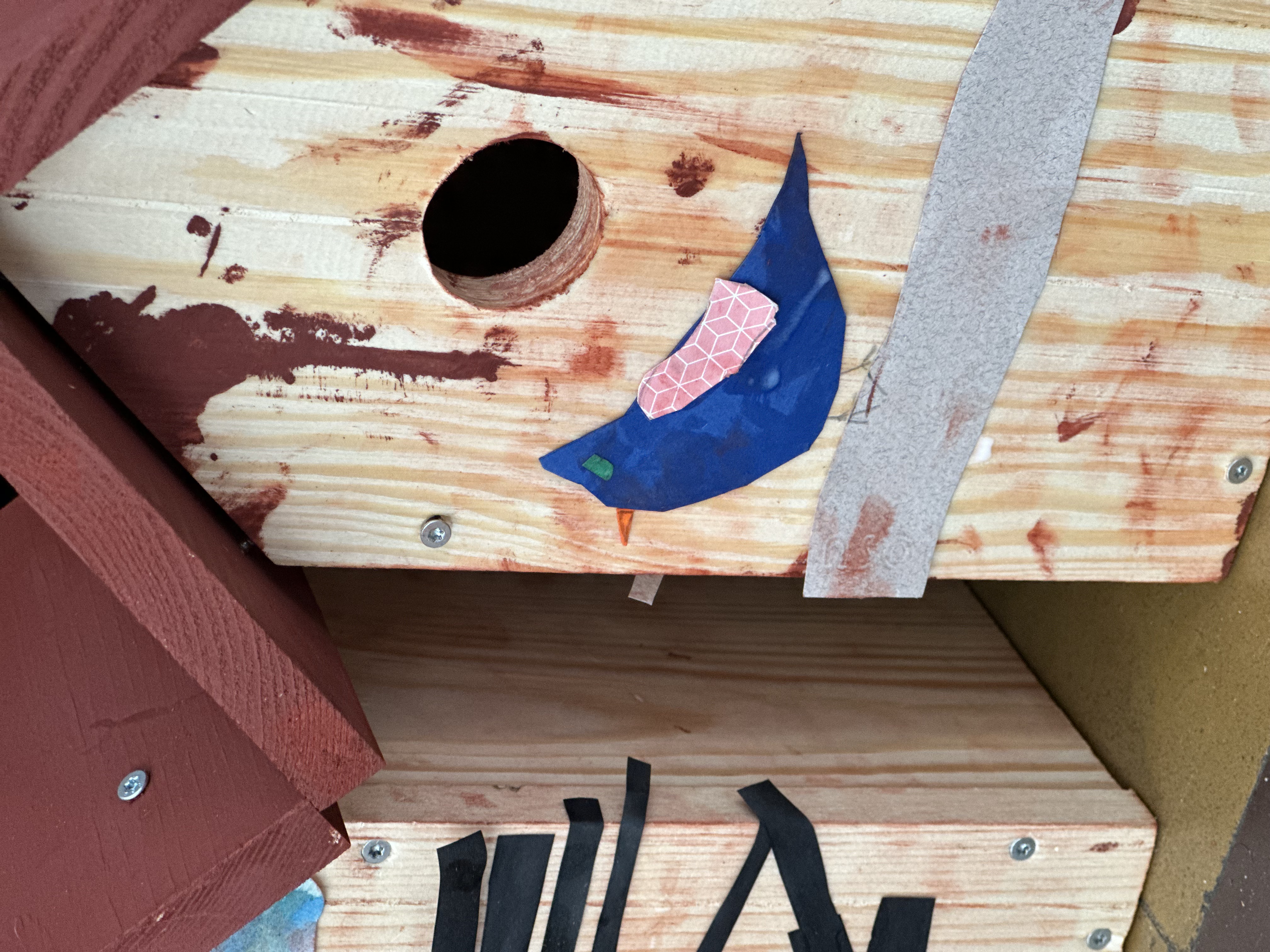 Détail créatif d'un nichoir d'enfant : oiseau bleu collé avec une aile rose