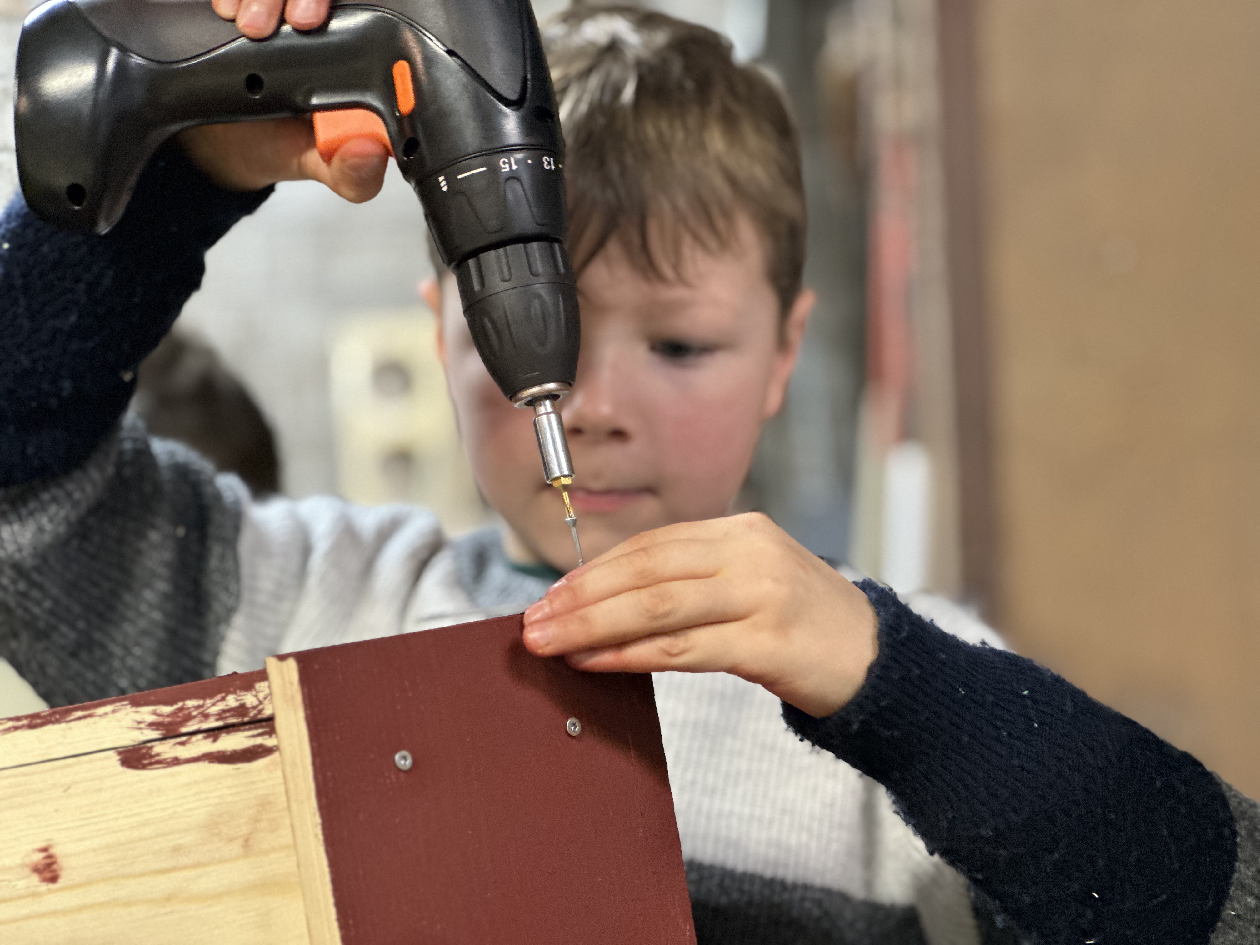 Un élève de 2ème primaire du CSM visse une pièce de son nichoir à la perceuse
