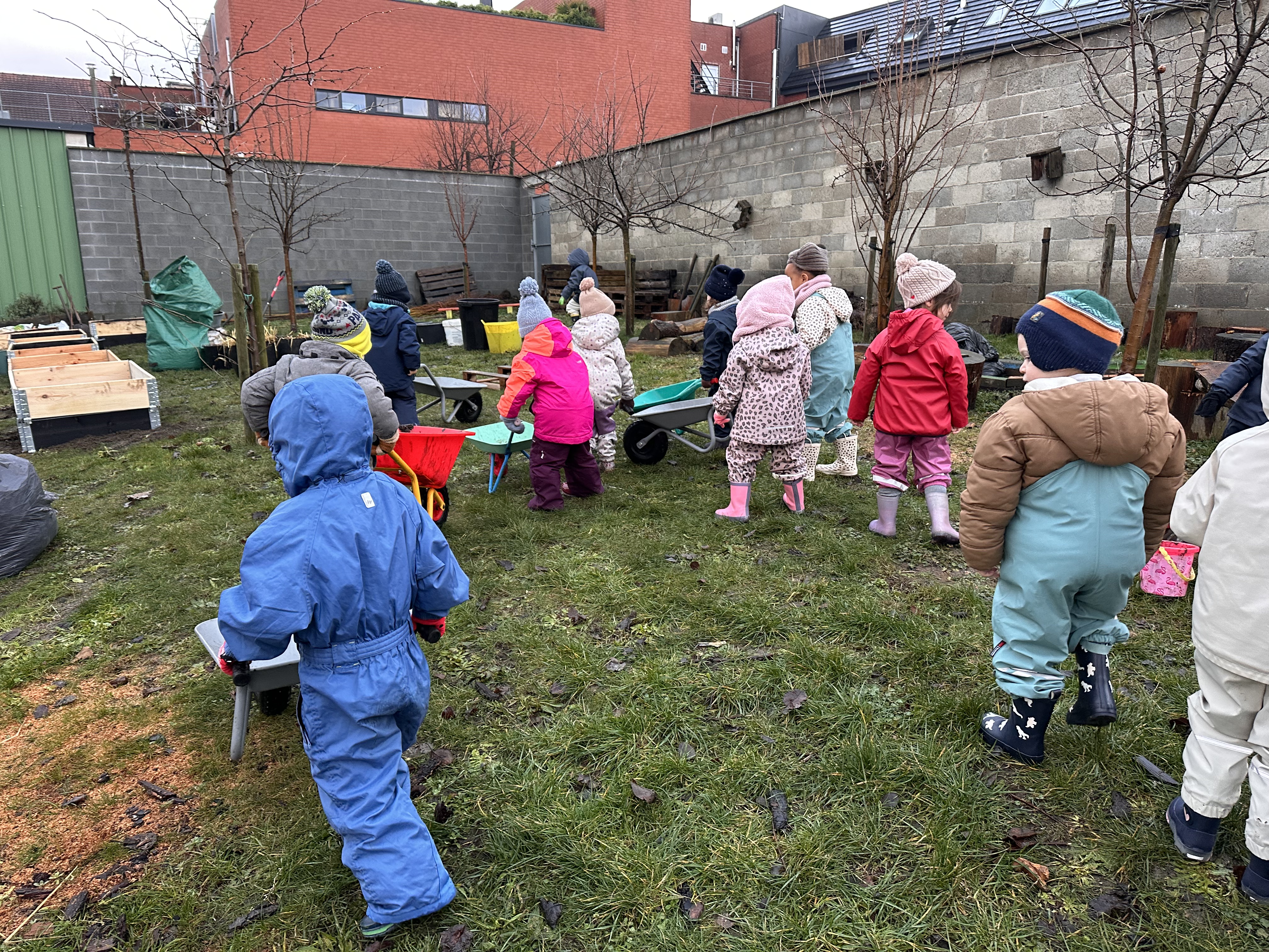 Enfants de maternelle du CSM avançant dans le jardin avec leurs brouettes