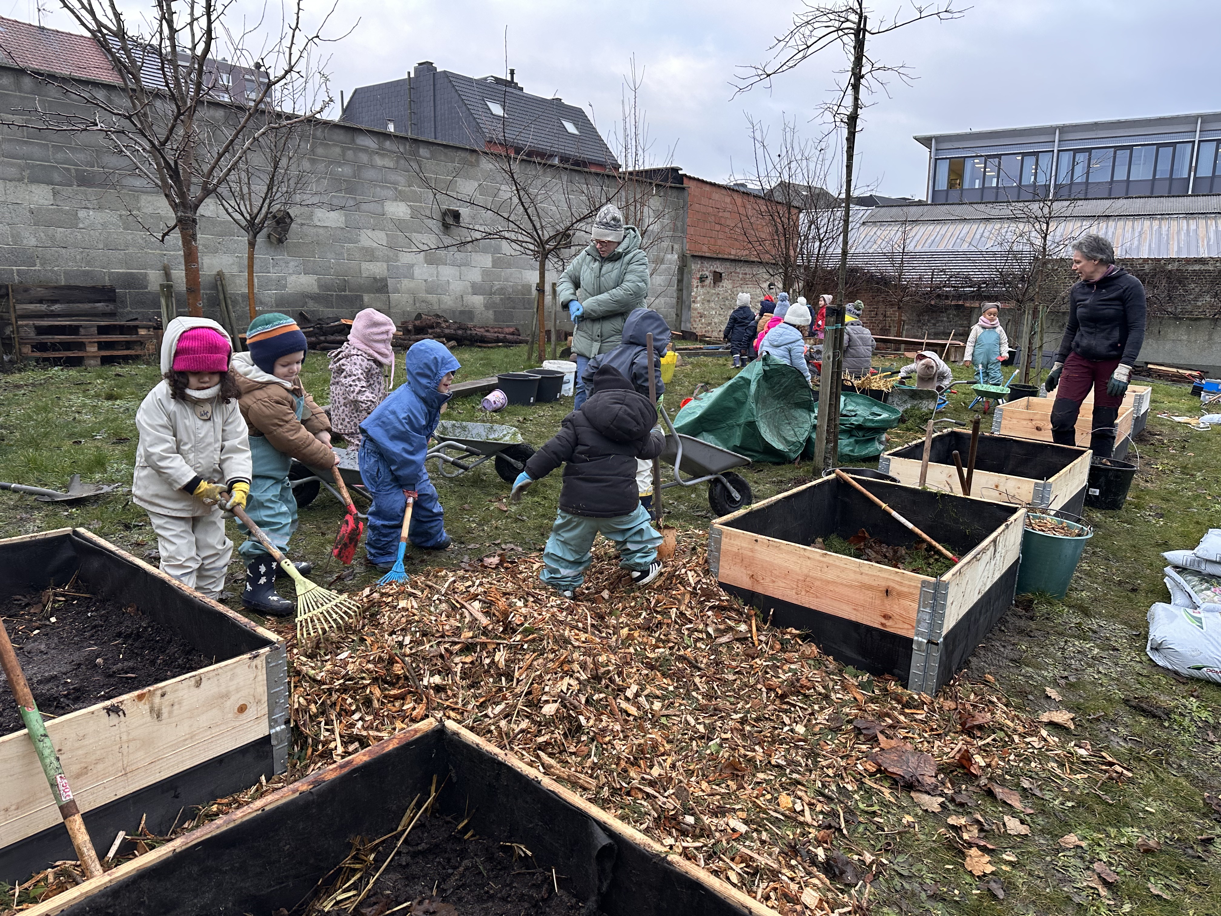 Enfants de maternelle du CSM travaillant le potager avec leurs outils et des copeaux de bois