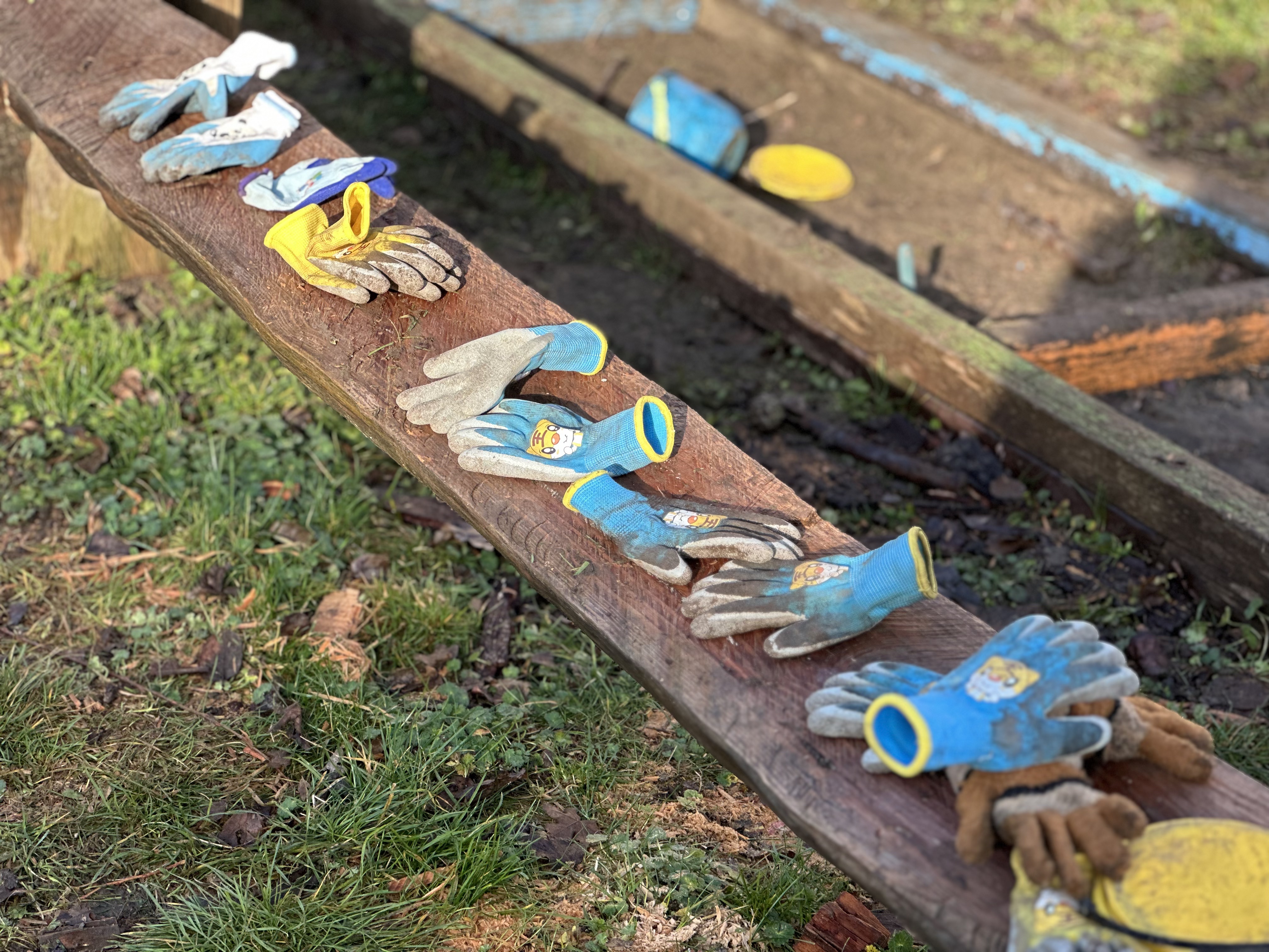 Paires de gants d'enfants pleins de terre posés sur un banc après l'atelier potager au CSM