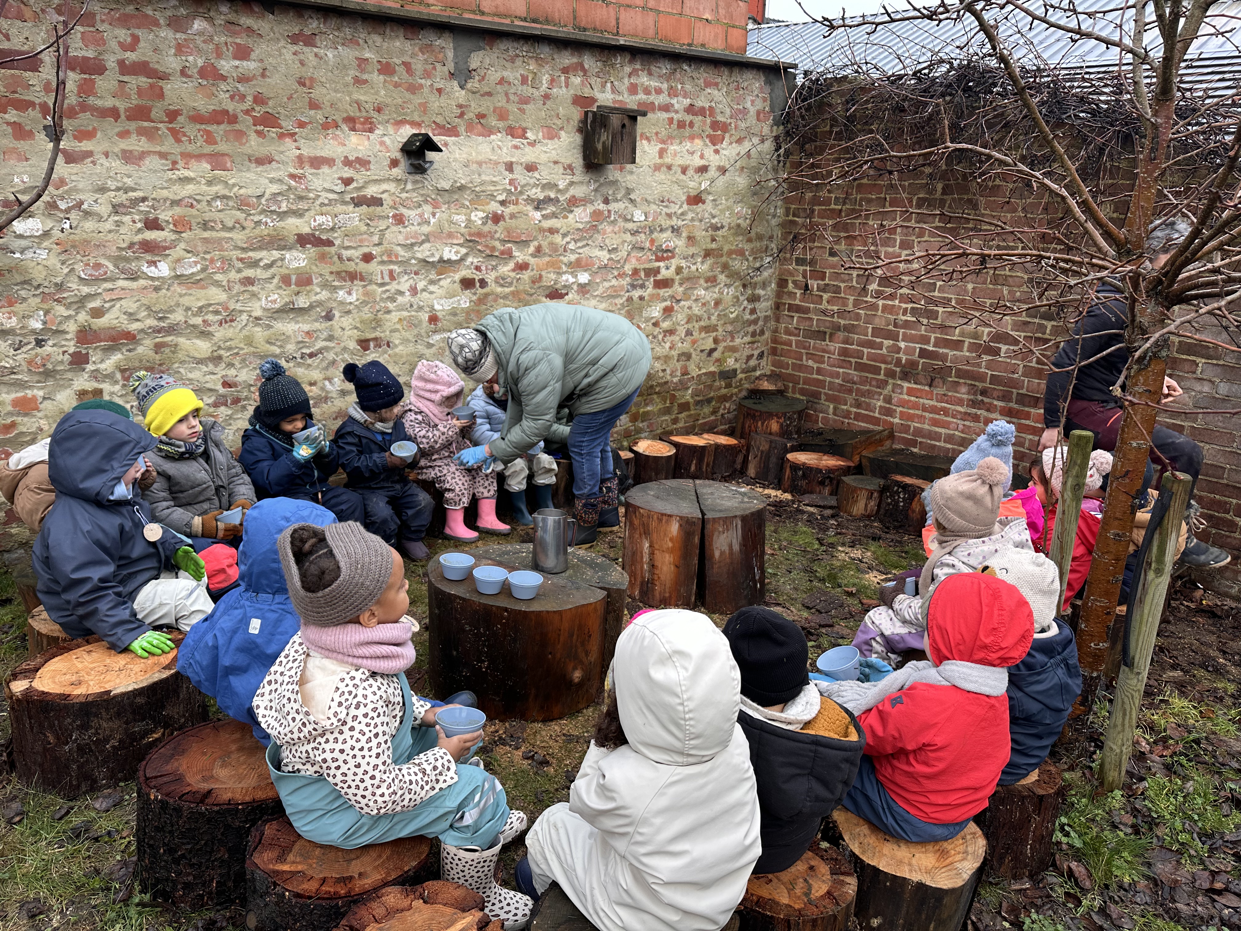 Enfants de maternelle du CSM partageant un moment sur les rondins du potager
