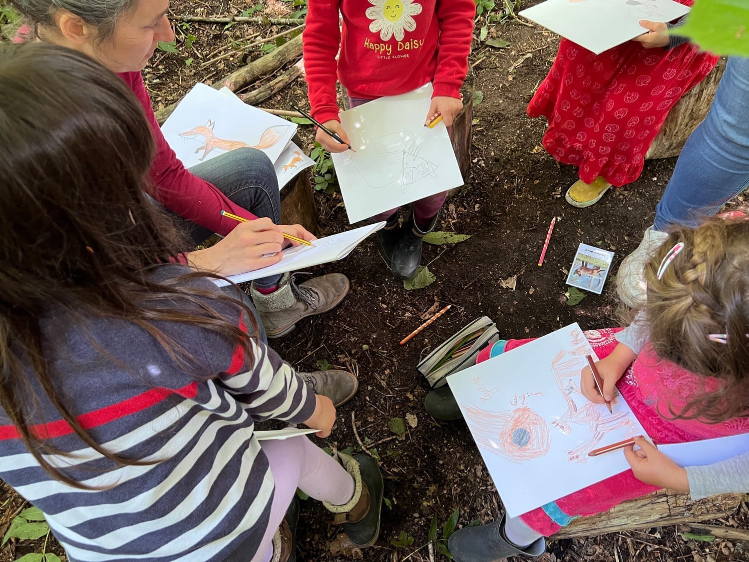 Enfants dessinant ensemble en forêt lors d'un atelier nature