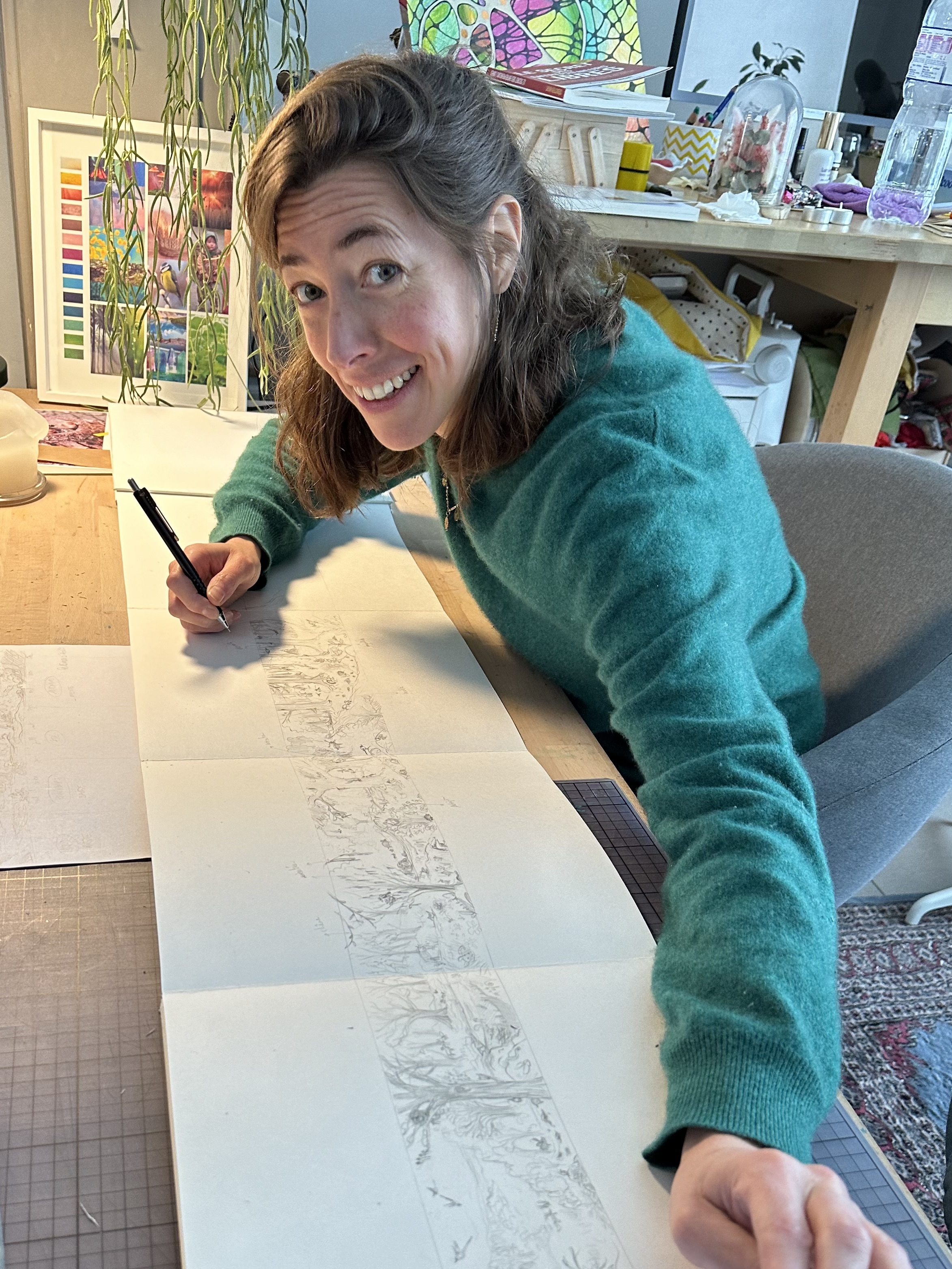 Hélène à son bureau, l'illustration du Calendrier Panoramique dépliée devant elle, montrant la longueur de la feuille