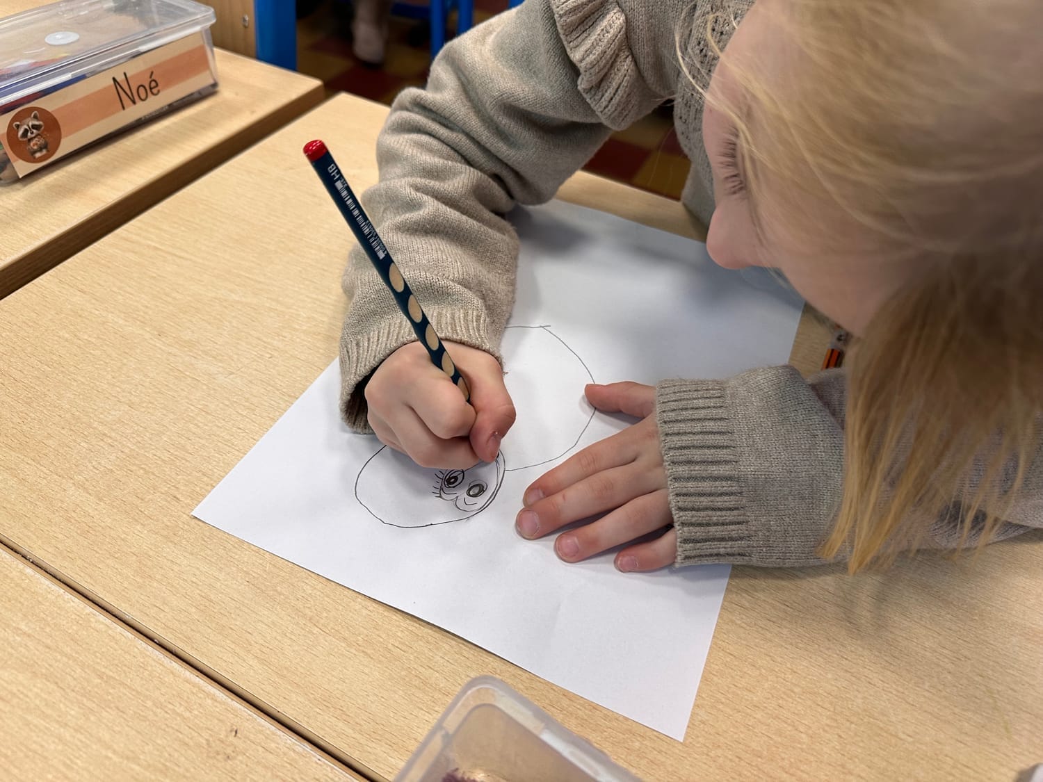 Petite fille concentrée sur le dessin de sa chouette hulotte en classe