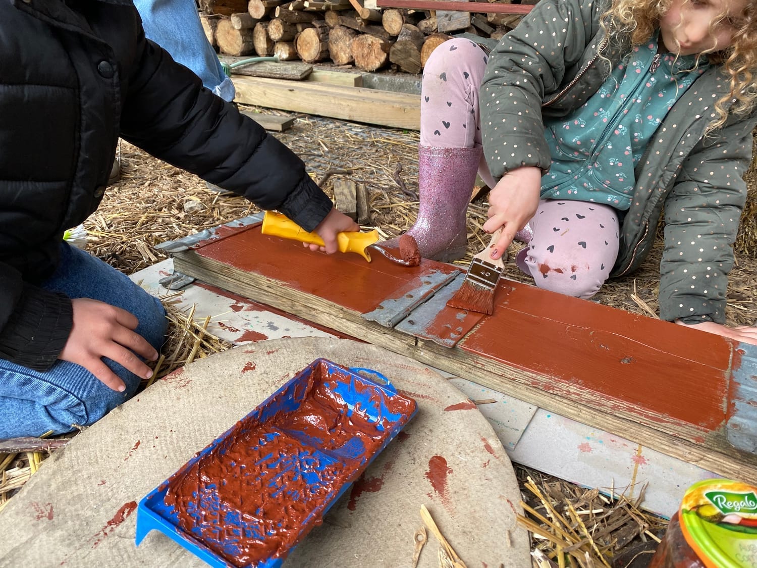 Enfants peignant les structures en bois du potager